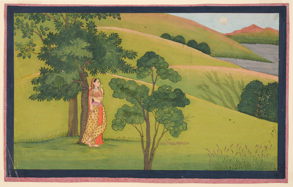 Radha stands in a windy field between two trees, looking into the distance for her love Krishna.